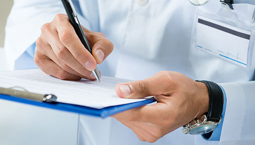 closeup of a person in a lab coat writing on notepad